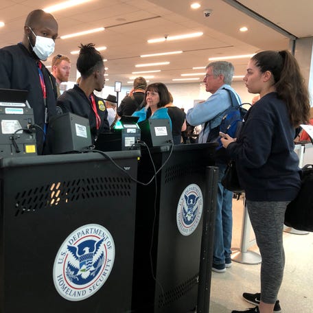 A U.S. Department of Homeland Security officer wears a protective face mask amid coronavirus fears as he checks passports for those departing from Fort Lauderdale-Hollywood International Airport in Fort Lauderdale, Florida, on March 15, 2020.