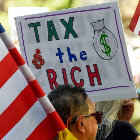 A protester carries a sign reading Tax the Rich during the No Kings Protest in downtown Montgomery, Ala., on Saturday morning October 18, 2025. About 600 people attended the march and rally.