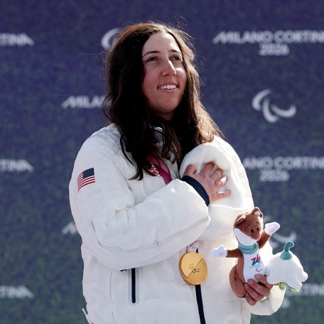 CORTINA D'AMPEZZO, ITALY - MARCH 13: Gold medallist Kate Delson of Team United States, sings the national anthem on the podium during the medal ceremony for the Para Snowboard Women's Banked Slalom SB-LL2 on day seven of the Milano Cortina 2026 Winter Paralympic Games at Cortina Para Snowboard Park on March 13, 2026 in Cortina d'Ampezzo, Italy. (Photo by Maja Hitij/Getty Images)