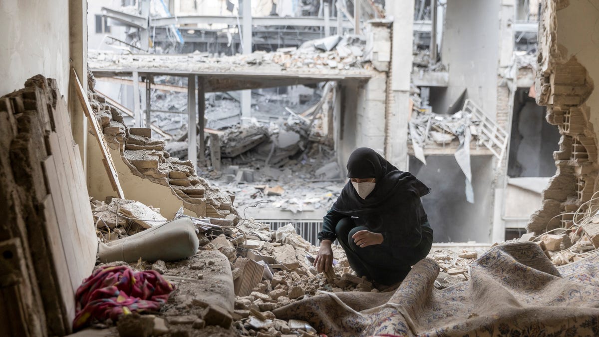 A woman sifts through rubble in the Beryanak District after missile attacks in Tehran, Iran, damaged her house.