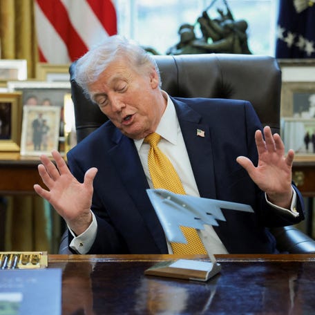 U.S. President Donald Trump looks at a model of a B‑2 bomber commemorating "Operation Midnight Hammer" during an event to sign an executive order creating an anti‑fraud task force headed by U.S. Vice President JD Vance in the Oval Office at the White House in Washington, D.C., U.S., March 16, 2026.