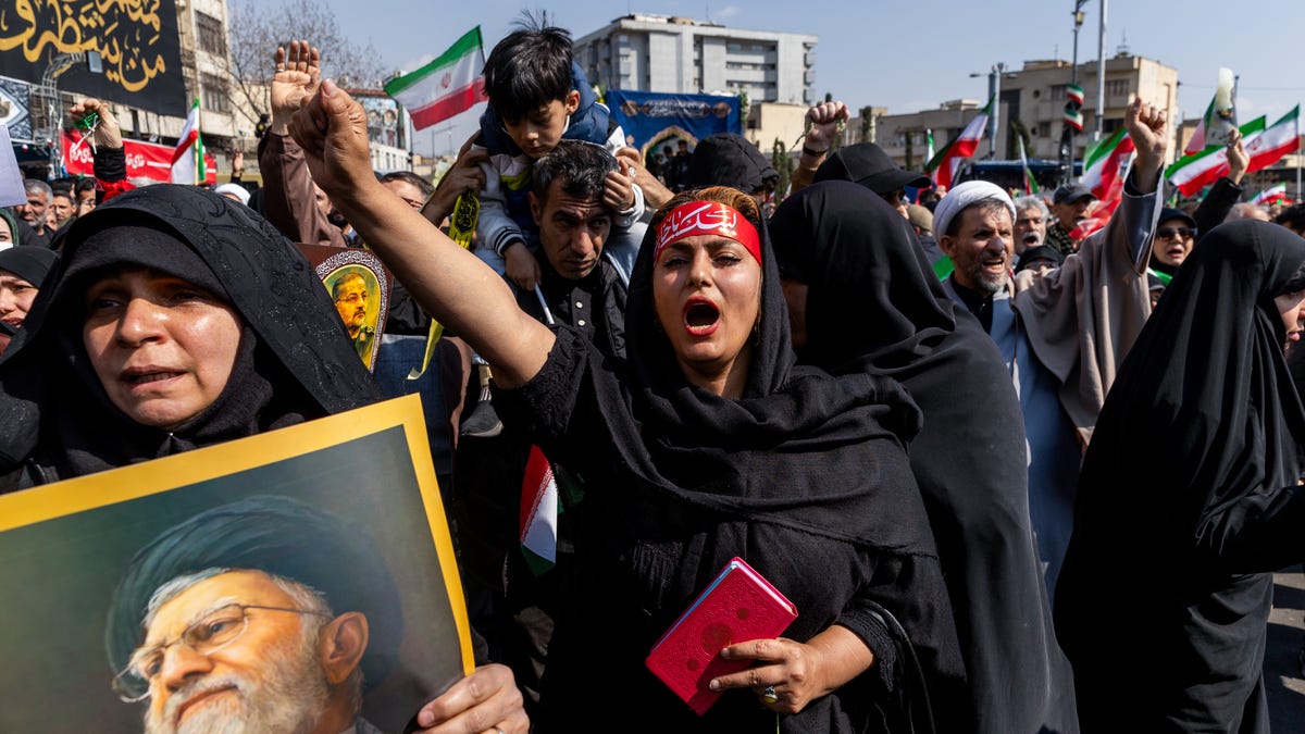 Members of the crowd react during a joint funeral for Ali Larijani, Secretary of Iran's Supreme National Security Council, Basij commander Major General Gholam Soleimani, and 84 sailors from the Iranian Navy frigate IRIS Dena, on March 18, 2026 in Tehran, Iran.
