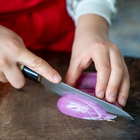 A10-year-old girl cutting shallots with a knife while cooking at home in Lyon, France on October 10, 2025. (Photo by Antoine Boureau / Hans Lucas via AFP) (Photo by ANTOINE BOUREAU/Hans Lucas/AFP via Getty Images)
