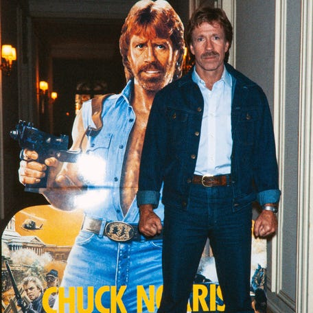 Chuck Norris poses on Nov. 27, 1985 in front of the poster for the movie "Invasion USA" at the Hôtel Plaza Athénée in Paris.