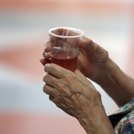 A picture taken on July 22, 2013, shows an old woman holding a glass in the Ehpad retirement home "Maison d'Aquitaine" in Merignac, southwestern France, during a visit of French Junior Minister for the Elderly. (Photo by NICOLAS TUCAT/AFP via Getty Images)