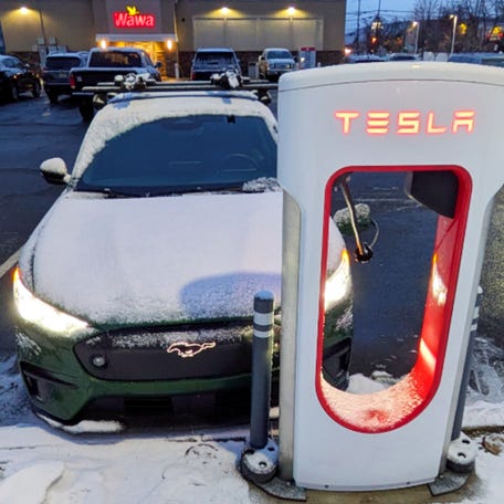 The 2025 Ford Mustang Mach-E Rally in Eruption Green Metallic is charging at a Tesla Supercharger.