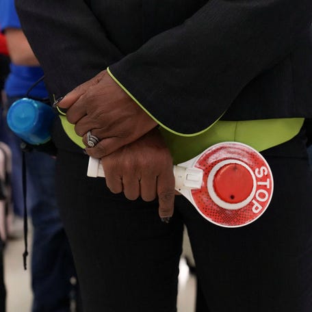 An airport employee holds a stop-and-go light-up sign while directing passengers waiting in long TSA lines amid a partial government shutdown, at Hartsfield-Jackson Atlanta International Airport in Atlanta, Georgia, on March 20, 2026.