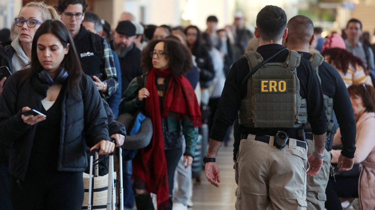 Federal agents patrol as people wait in line at New York's LaGuardia Airport in Queens, New York, on March 24, 2026.