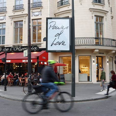 A man rides his bicycle past a billboard displaying a poster with the title of the song "Power of Love" by singer Celine Dion in a street in Paris, France on March 24, 2026.