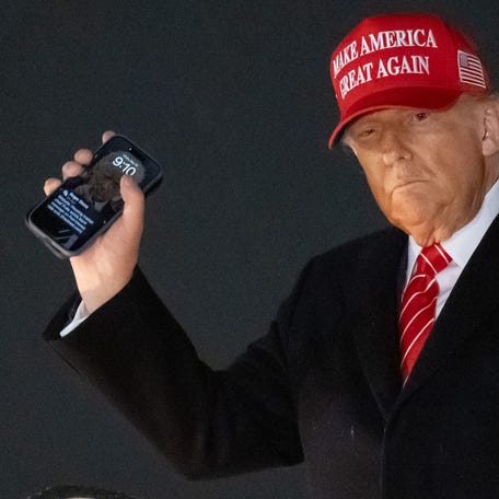 US President Donald Trump disembarks from Air Force One while holding his cellphone with a text message from Roger Stone upon arrival at Joint Base Andrews in Maryland, May 30, 2025, after traveling to Pennsylvania to visit a US Steel plant.