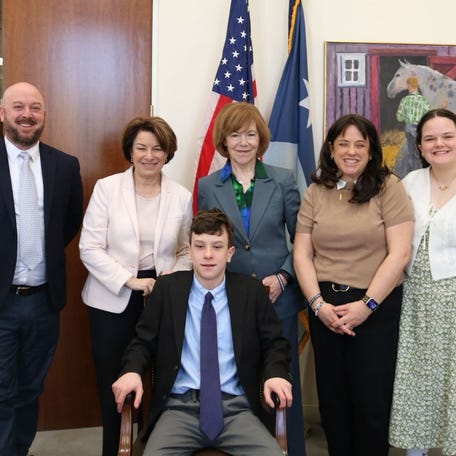 Annunciation Catholic Church and School shooting survivor, Victor Greenawalt, poses with Sen. Amy Klobuchar and Sen. Tina Smith.