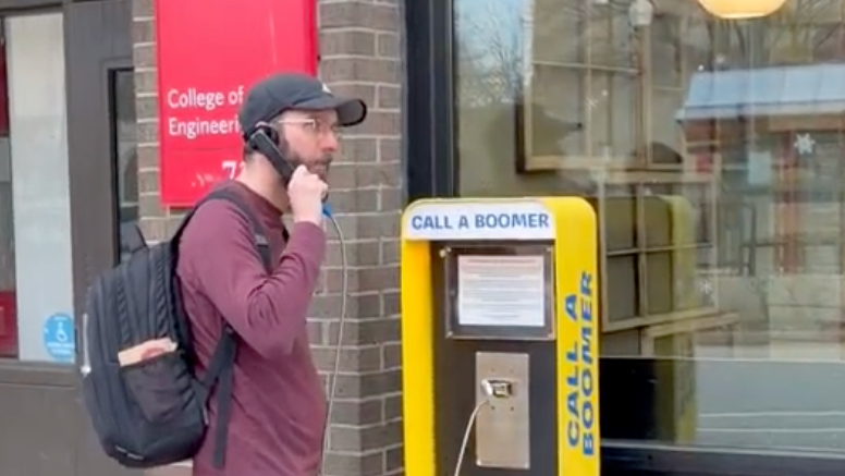 The "Call a Boomer" payphone sits out of a coffee shop in Boston.