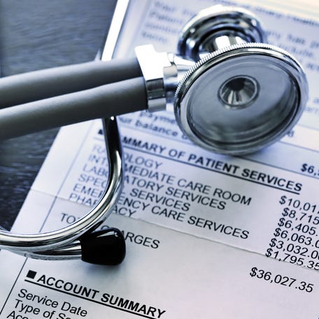 A stethoscope rests on top of a very expensive medical invoice that has line items for different services provided.