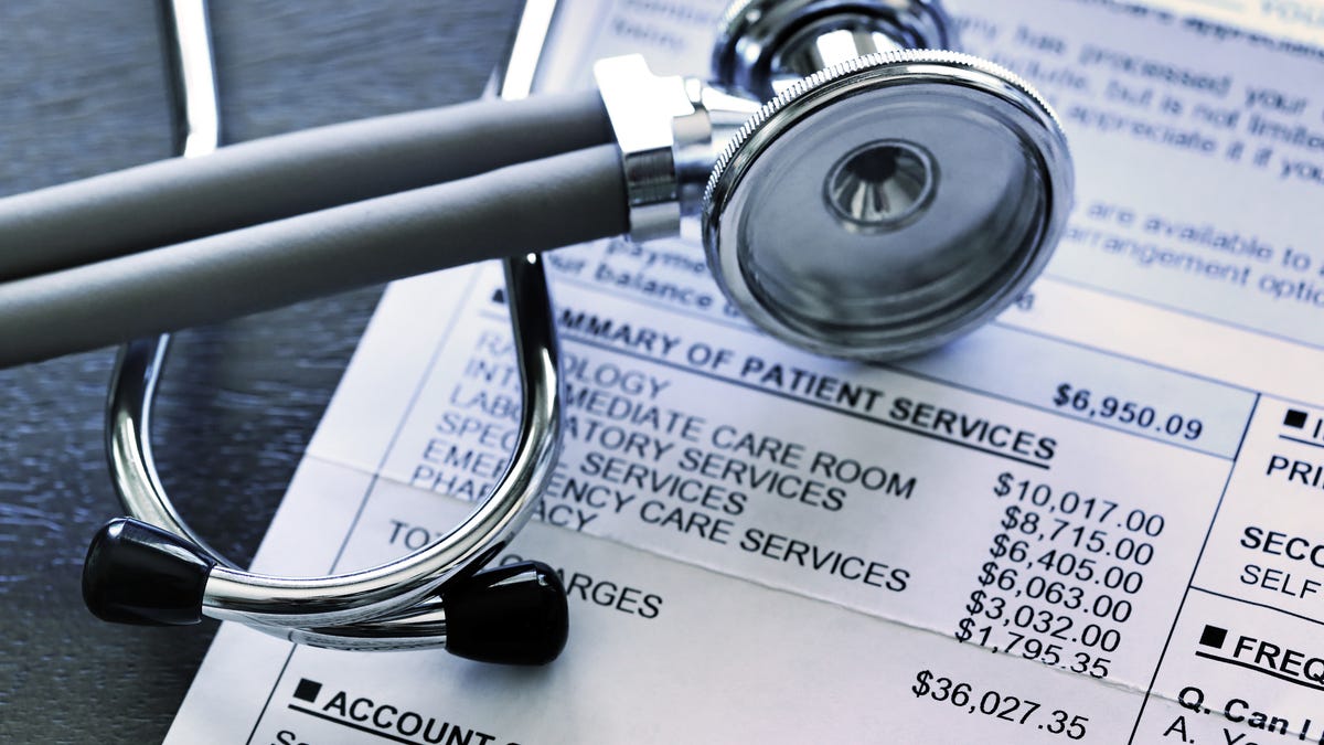 A stethoscope rests on top of a very expensive medical invoice that has line items for different services provided.