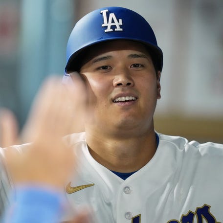 Los Angeles Dodgers designated hitter Shohei Ohtani shakes hands with teammates in the dugout after scoring a run against the Arizona Diamondbacks during the seventh inning at Dodger Stadium on March 26, 2026.