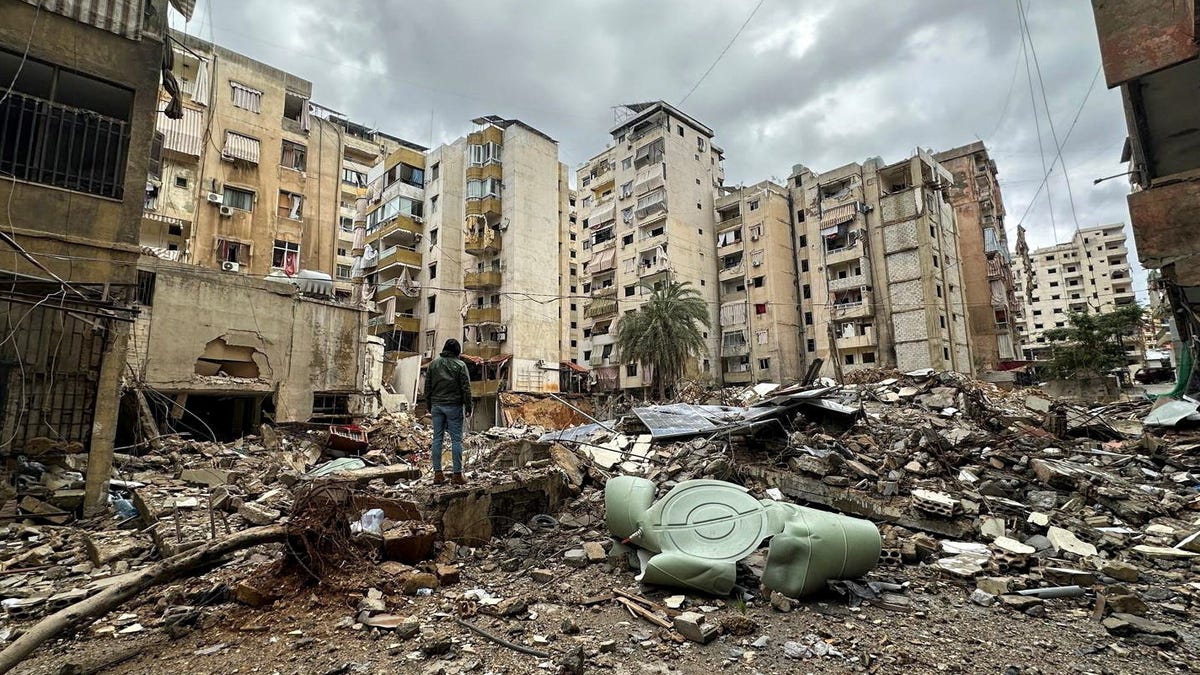 A man stands next to buildings damaged by Israeli strikes, amid escalating hostilities between Israel and Hezbollah, as the U.S.-Israel conflict with Iran continues, in Beirut's southern suburbs, Lebanon, March 27, 2026. Picture taken with a mobile phone.