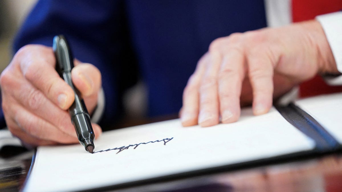 President Donald Trump writes his signature, as he signs executive orders and proclamations in the Oval Office at the White House on April 9, 2025.