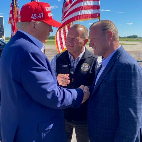 President Donald Trump shakes hands with Trever Nehls (right) and Rep. Troy Nehls (center), twin brothers.