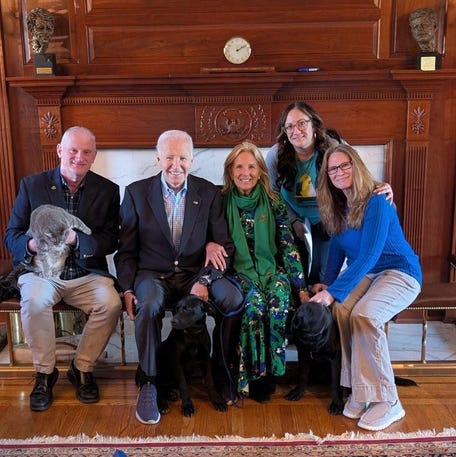 Former President Joe Biden and former first lady Jill Biden pose with their newly adopted black lab mix dogs.