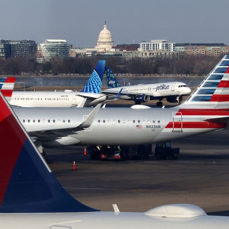 A JetBlue aircraft lands under the DC skyline featuring the U.S. Capitol building, near United Airlines, American Airlines and Delta Airlines aircraft on the tarmac at Ronald Reagan Washington National Airport on January 25, 2025.