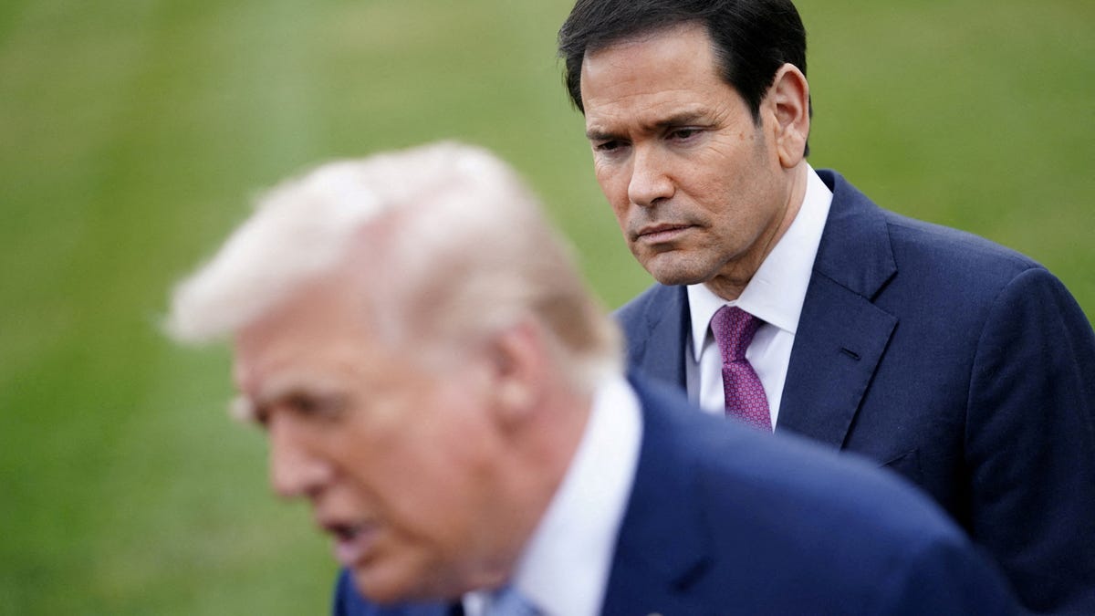 U.S. Secretary of State Marco Rubio listens to U.S. President Donald Trump speaking to the media, as Trump departs the White House for Florida, in Washington, D.C., U.S., March 20, 2026.