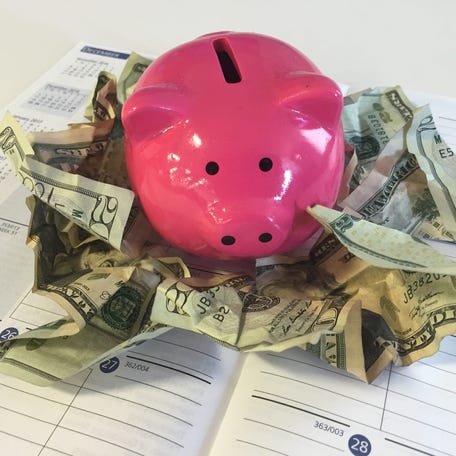 A piggy bank and dollar bills are pictured above a personal calendar.