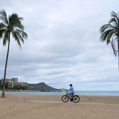 A cyclist rides along an empty Waikiki Beach.