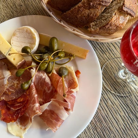 Assorted French cheeses and meats are served alongside bread and Kir at Bonvivant in Paris.