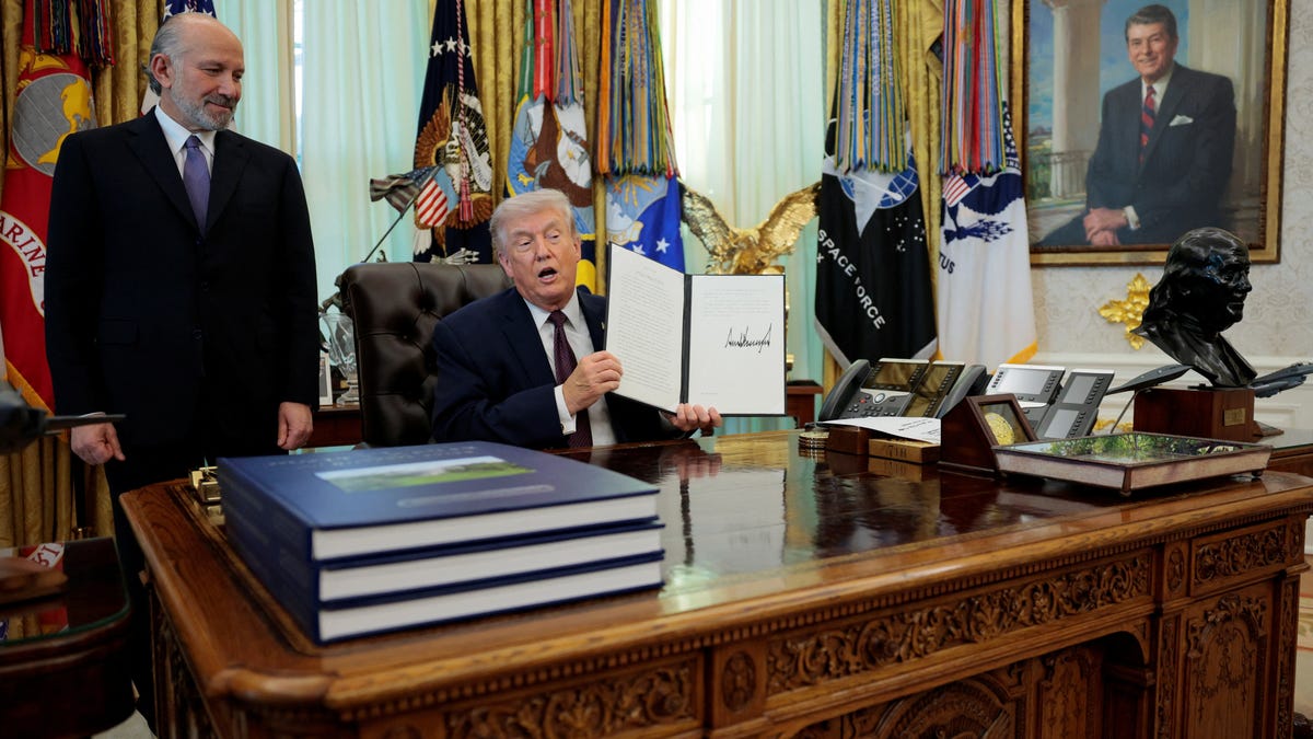 U.S. President Donald Trump speaks next to U.S. Commerce Secretary Howard Lutnick as he shows a signed executive order on mail ballots, in the Oval Office of the White House in Washington, D.C., March 31, 2026. REUTERS/Evan Vucci
