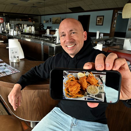 Jeffrey Paquette, owner of Pinecroft Dairy and Restaurant, shows off an image of the noted fish and chips.