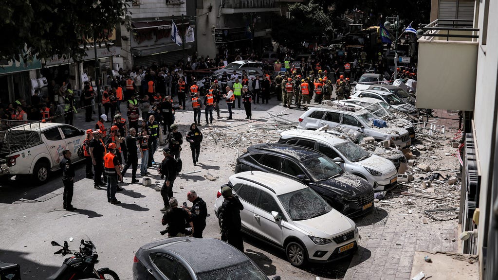 First responders gather along a street before a building that was hit by an Iranian projectile attack in Ramat Gan in central Israel on April 6, 2026.