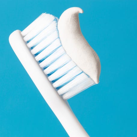 Toothbrush and toothpaste on blue background.