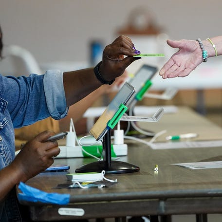 A Poll worker hands a person a voting card as voters head to the polls on April 7, 2026 in Lookout Mountain, Georgia. The special election is being held to fill the 14th congressional district seat.