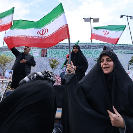 Iranians wave national flags in Tehran at a rally on April 8, 2026.