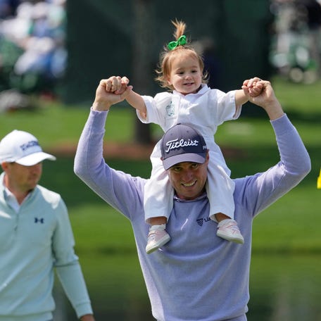 Justin Thomas holds his daughter Molly Grace on his shoulders on the fourth hole during the Par 3 Contest at the Masters Tournament at Augusta National Golf Club.