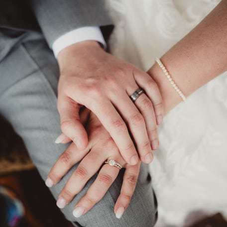 Man and woman with hands showing off engagement ring and wedding band