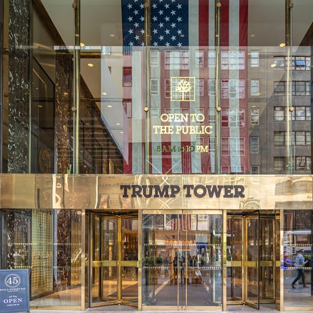 The main entrance of Trump Tower with the inscription on it and a US flag in New York City in the United States of America.