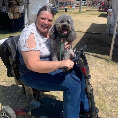 Debi Coleman in her mobility scooter with her service dog, Darby.