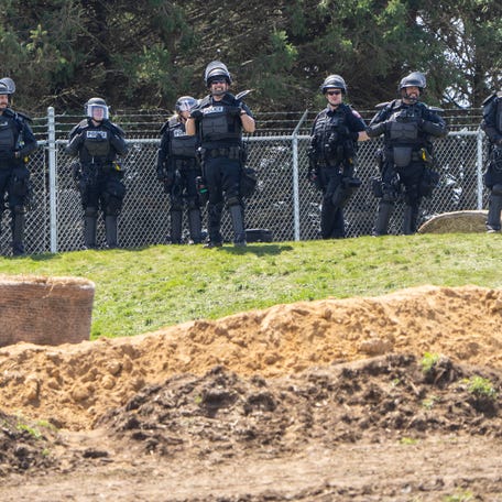 Law enforcement personnel stand between about 1,000 people and the medical research dog breeder Ridglan Farms Saturday, April 18, 2026 in rural Dane County near Blue Mounds, Wisconsin. Ridglan Farms is licensed by the state as a dog breeding operation. It breeds thousands of beagles and sells them to laboratories for medical and scientific testing and has operated for nearly 60 years.