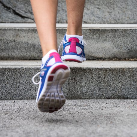 Legs only close-up shot of female runner climbing a grey stone staircase.