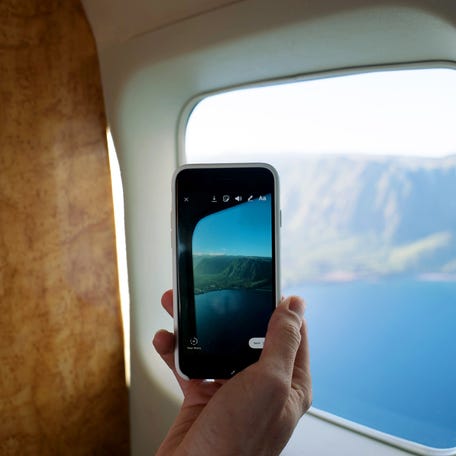Phone taking photo of plane view over Molokai.