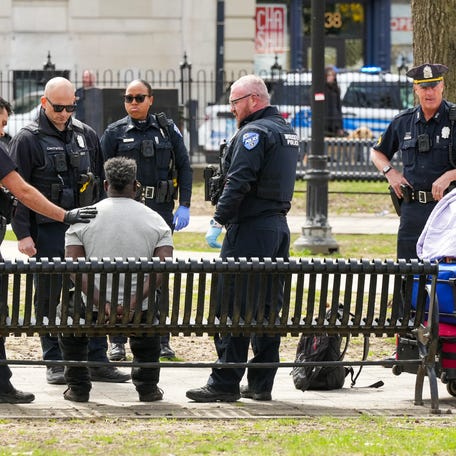Worcester police officers speak to a man after a disturbance on the Common the afternoon of April 21. He was handcuffed and taken away by ambulance.
