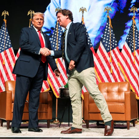 Republican presidential nominee and former U.S. President Donald Trump shakes hands with Tucker Carlson at 'Tucker Carlson Live on Tour' at Desert Diamond Arena, in Glendale, Arizona, U.S. October 31, 2024.