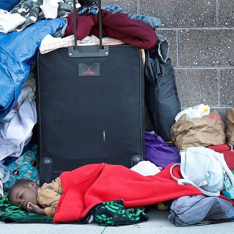 One year old Roseline Ridore sleeps next to her families belongings on Aug. 27, 2024. Homeless Haitian immigrants gathered at the Wollaston MBTA station in Quincy, Mass.