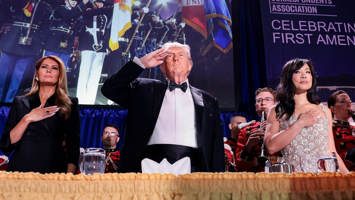 U.S. President Donald Trump, with first lady Melania Trump and CBS News senior White House correspondent Weijia Jiang, salutes during the annual White House Correspondents' Association dinner in Washington, D.C., U.S., April 25, 2026.