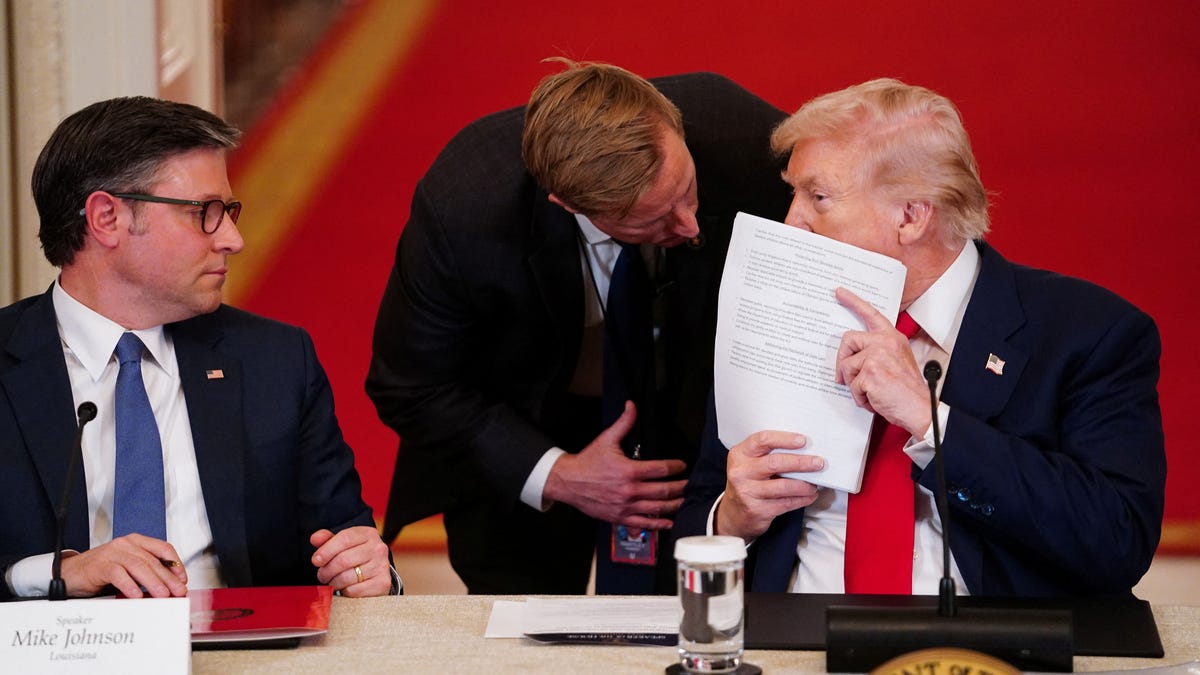 House Speaker Mike Johnson, R-Louisiana, looks on as a member of the Secret Service speaks with President Donald Trump during a White House meeting in Washington, DC, on March 6, 2026.