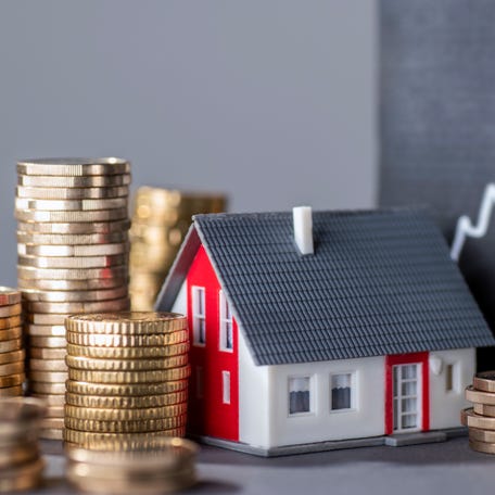 House with stacks of money and a rising curve symbolizing rising real estate prices