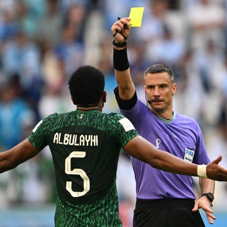 TOPSHOT - Slovenian referee Slavko Vincic (R) shows a yellow card to Saudi Arabia's defender #05 Ali Al-Bulaihi during the Qatar 2022 World Cup Group C football match between Argentina and Saudi Arabia at the Lusail Stadium in Lusail, north of Doha on November 22, 2022.