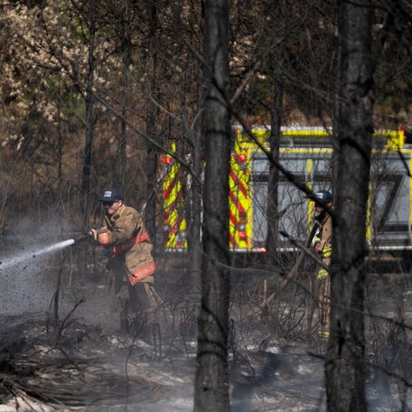 A firefighter uses a hose to blast a hot spot from the Brantley Highway 82 Fire on April 24, 2026, in Atkinson, Georgia. The wildfire is one of many burning in the southeastern United States.