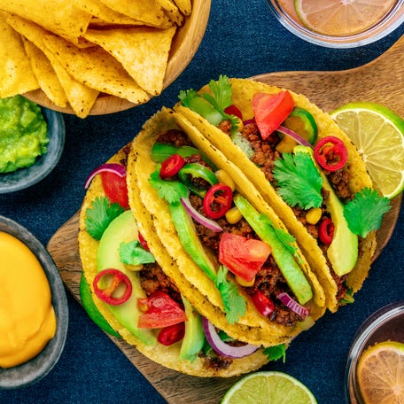 Beef tacos, nachos, salsas, Mexican food, overhead flat lay shot on a vibrant blue background